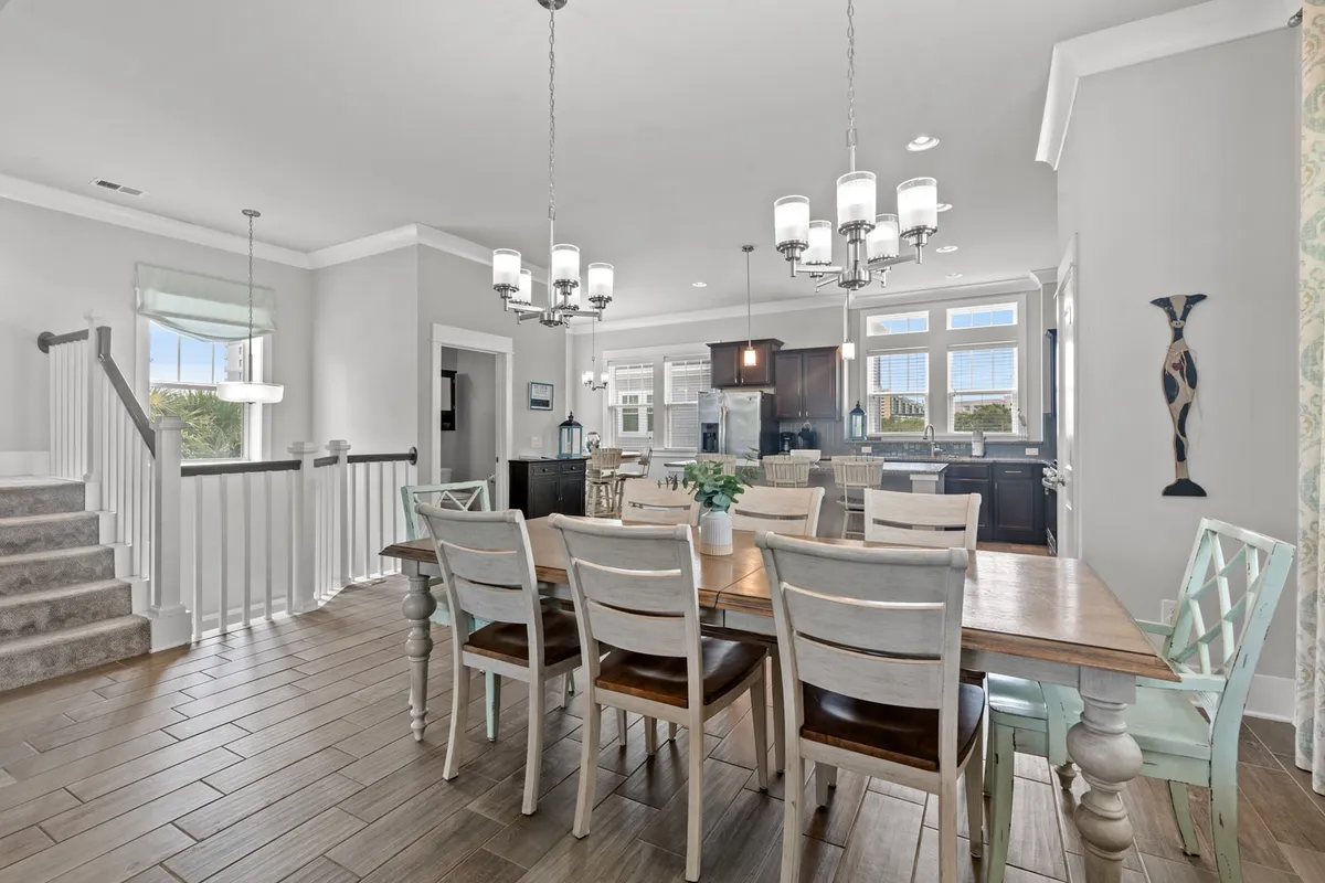 A large, welcoming dining area seamlessly connected to a modern kitchen and an adjacent staircase. The dining table is spacious, ideal for family meals or festive celebrations, and the kitchen area in the background highlights modern amenities.