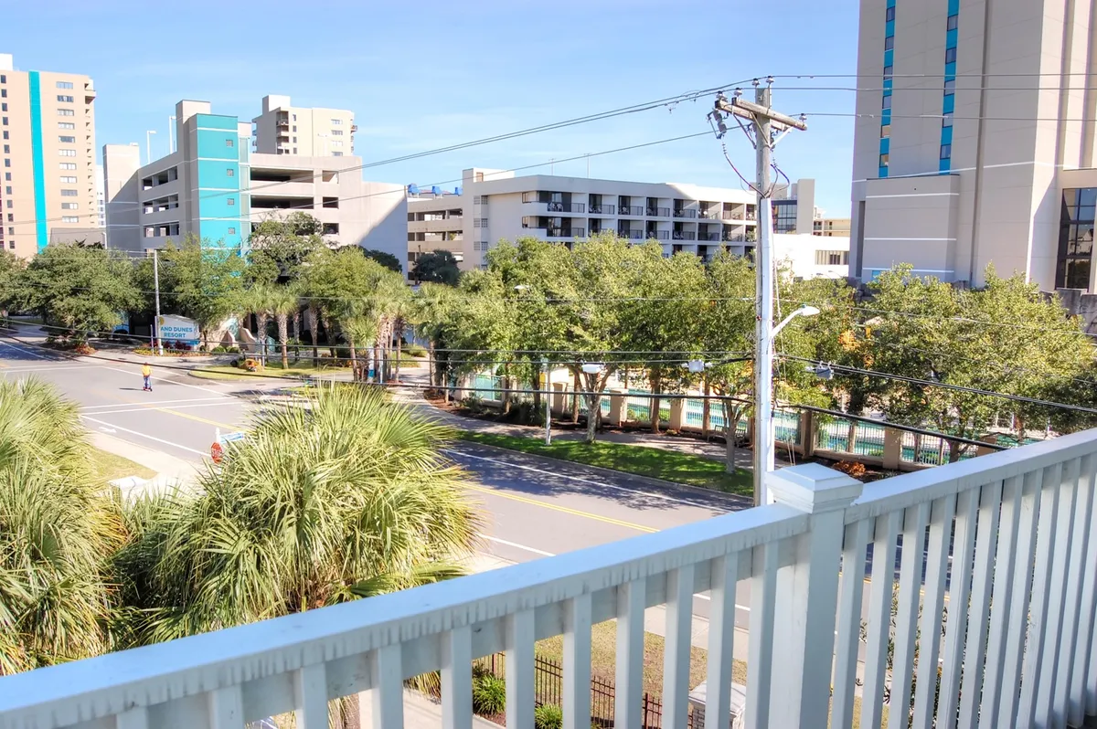 A cheerful view overlooking palm trees, a sparkling swimming pool, and modern buildings, hinting at leisure activities and community events. The scene suggests daytime relaxation and sets the stage for fun with friends before heading out for nightlife activities.